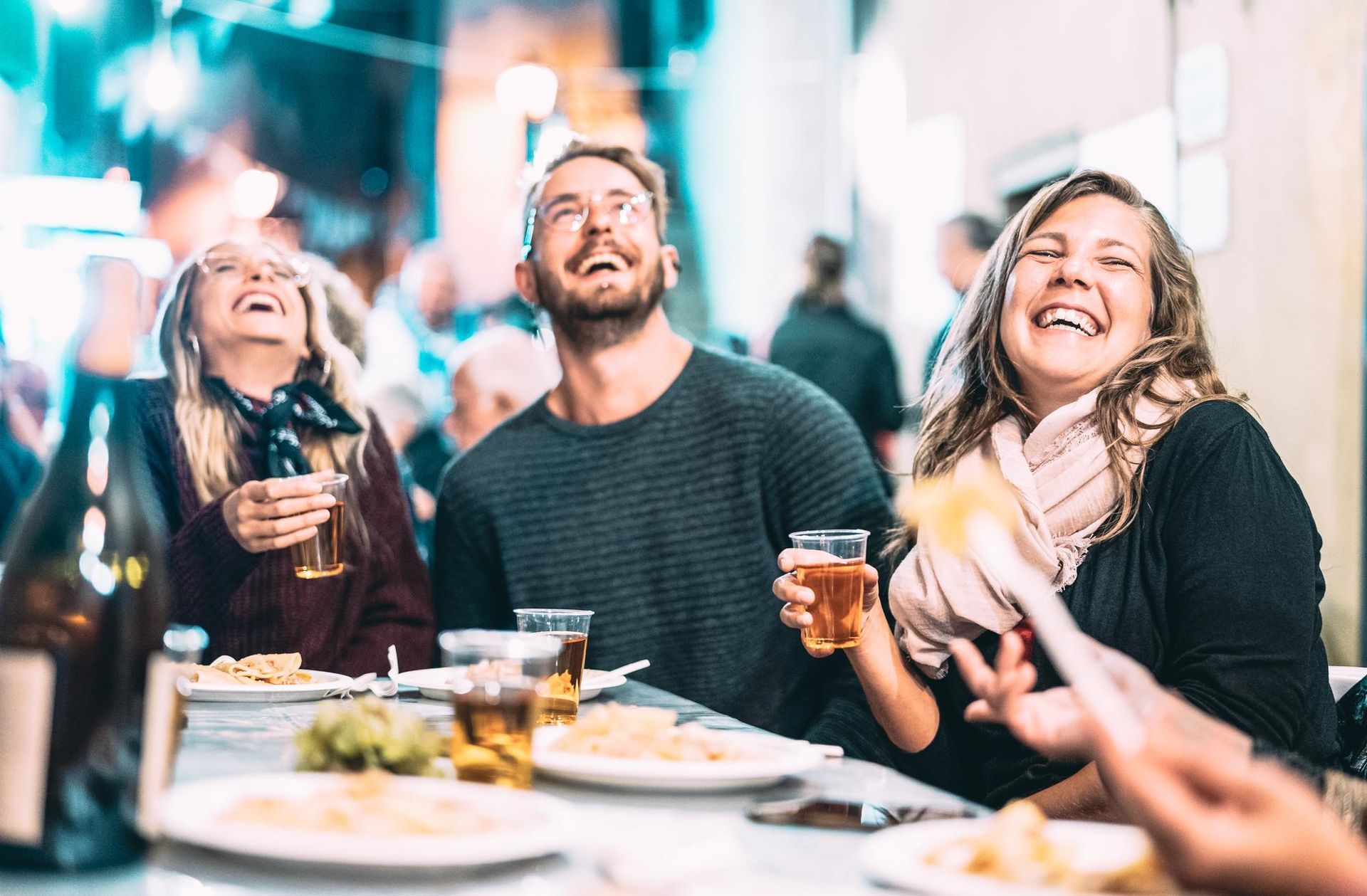 A group of people are sitting at a table eating food and drinking beer. 