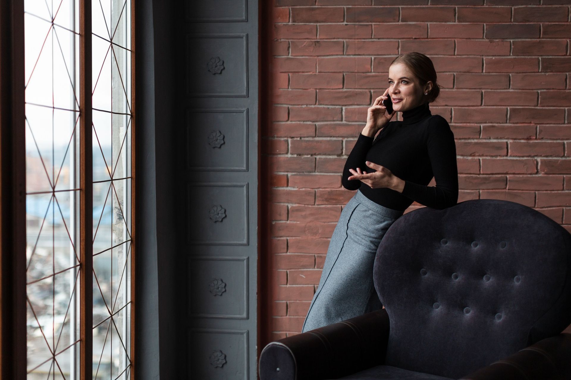 A woman is sitting in a chair talking on a cell phone. 