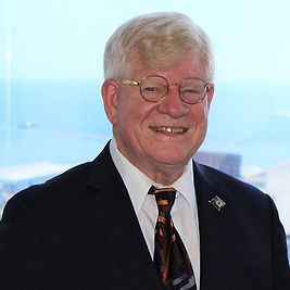 A man in a suit and tie is smiling in front of a window.