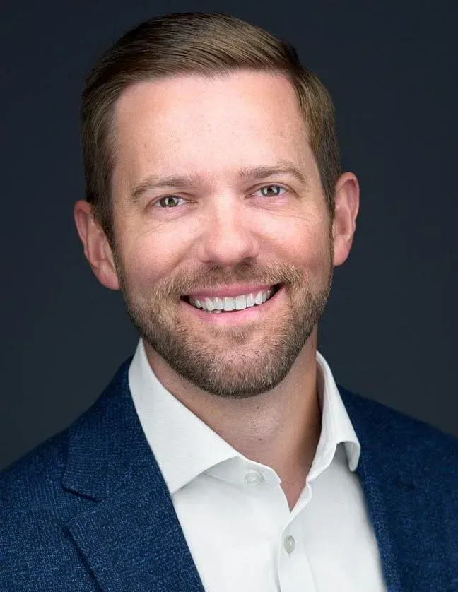 A man in a suit and white shirt is smiling for the camera.