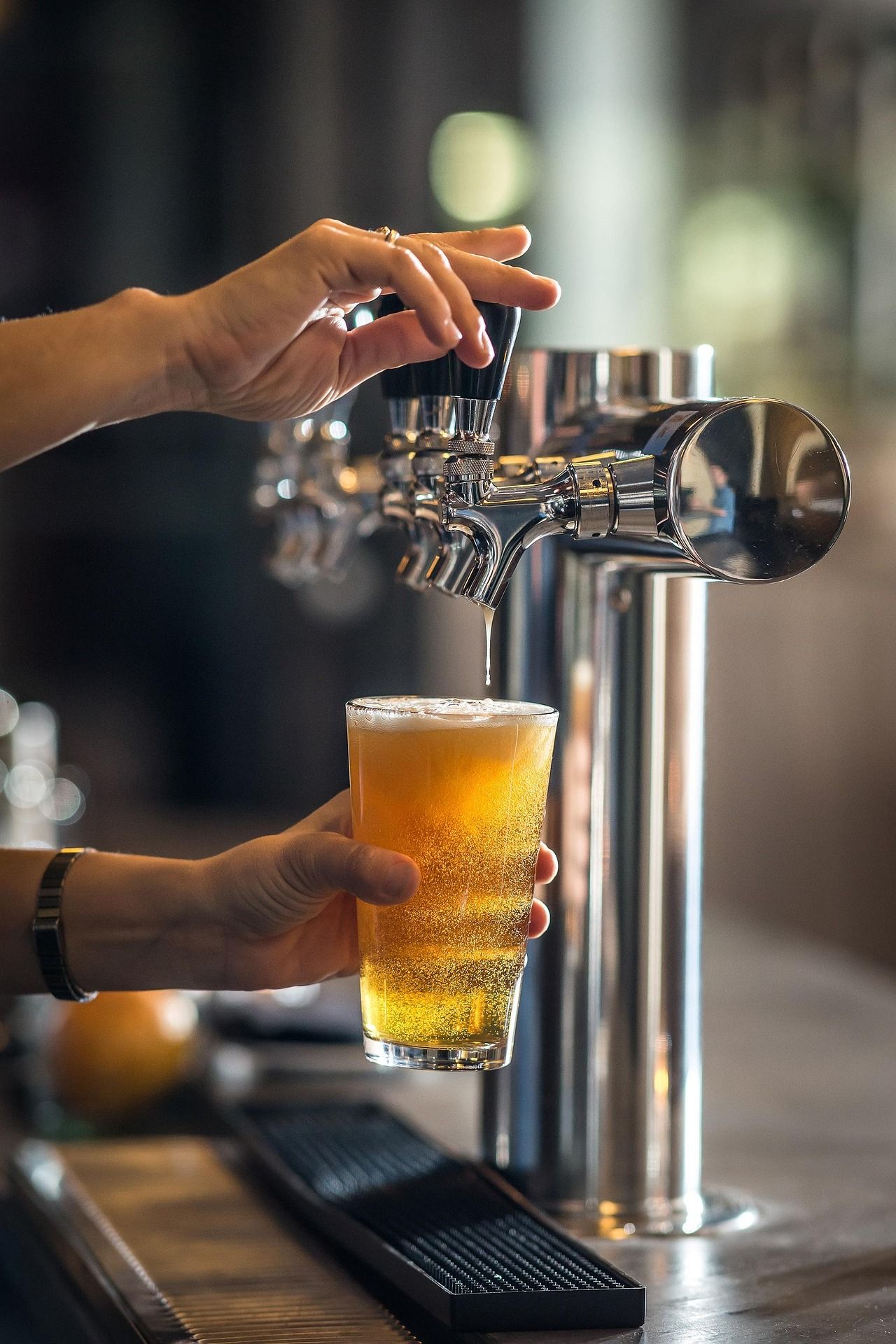 A person is pouring beer into a glass at a bar. 
