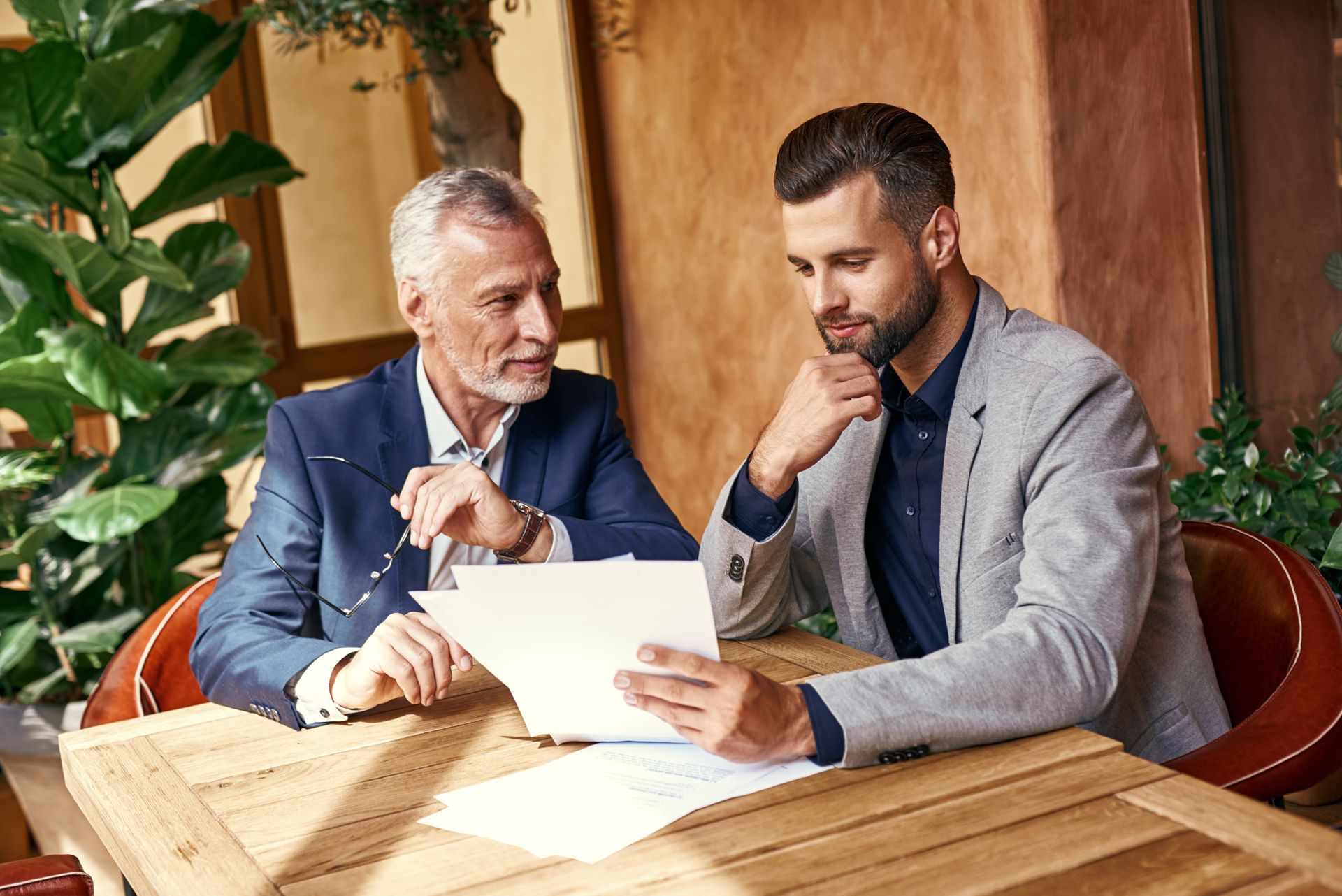 Two men are sitting at a table looking at a piece of paper.