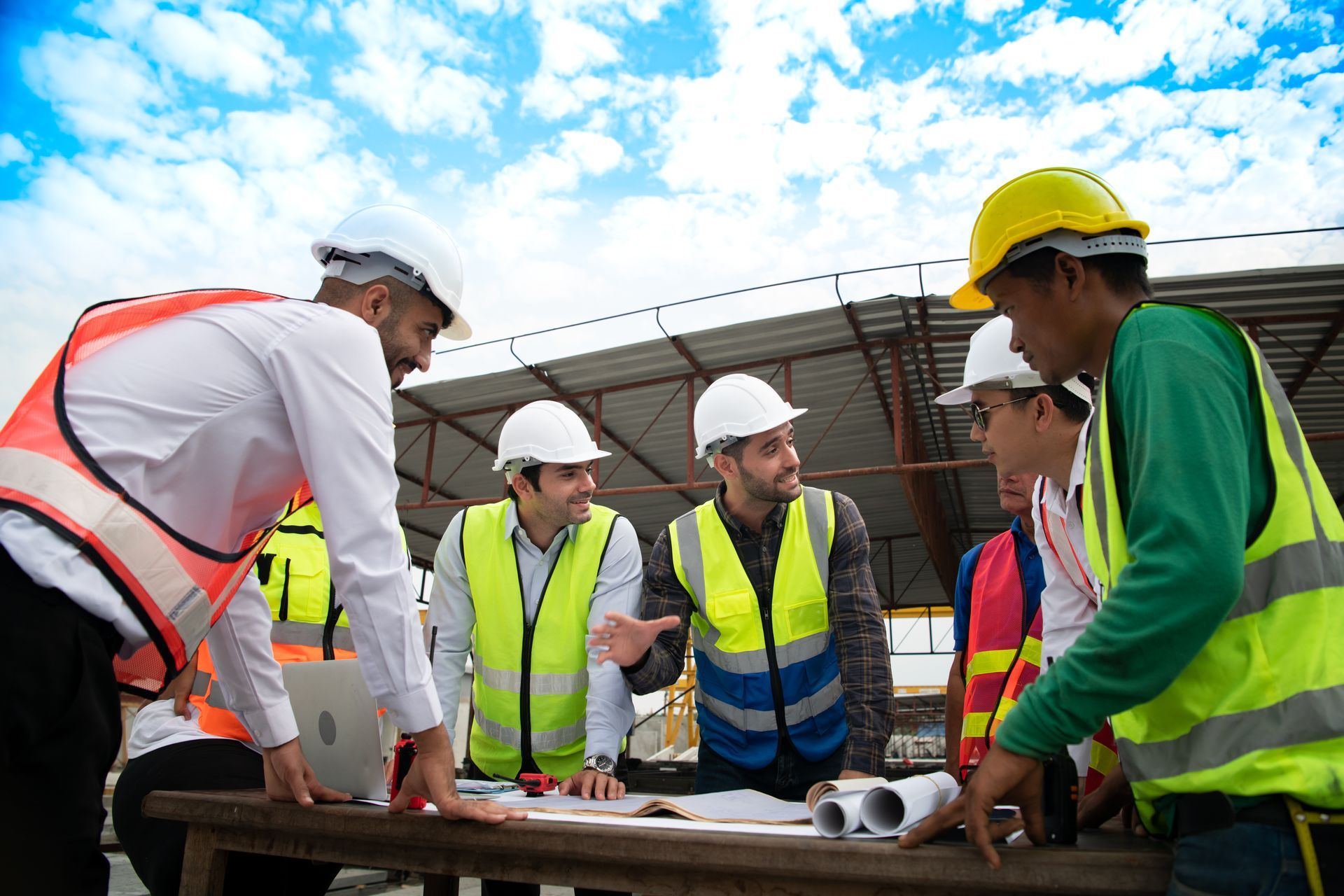 A group of construction workers are having a meeting at a table. 