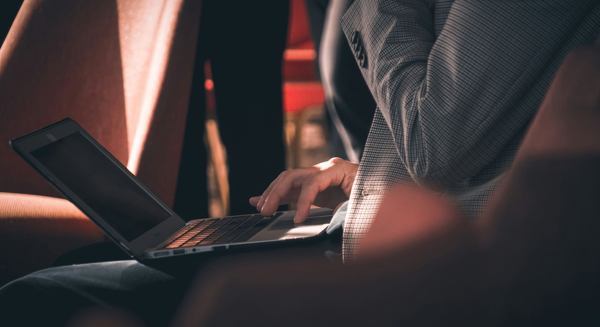 A person is sitting in a chair using a laptop computer. 