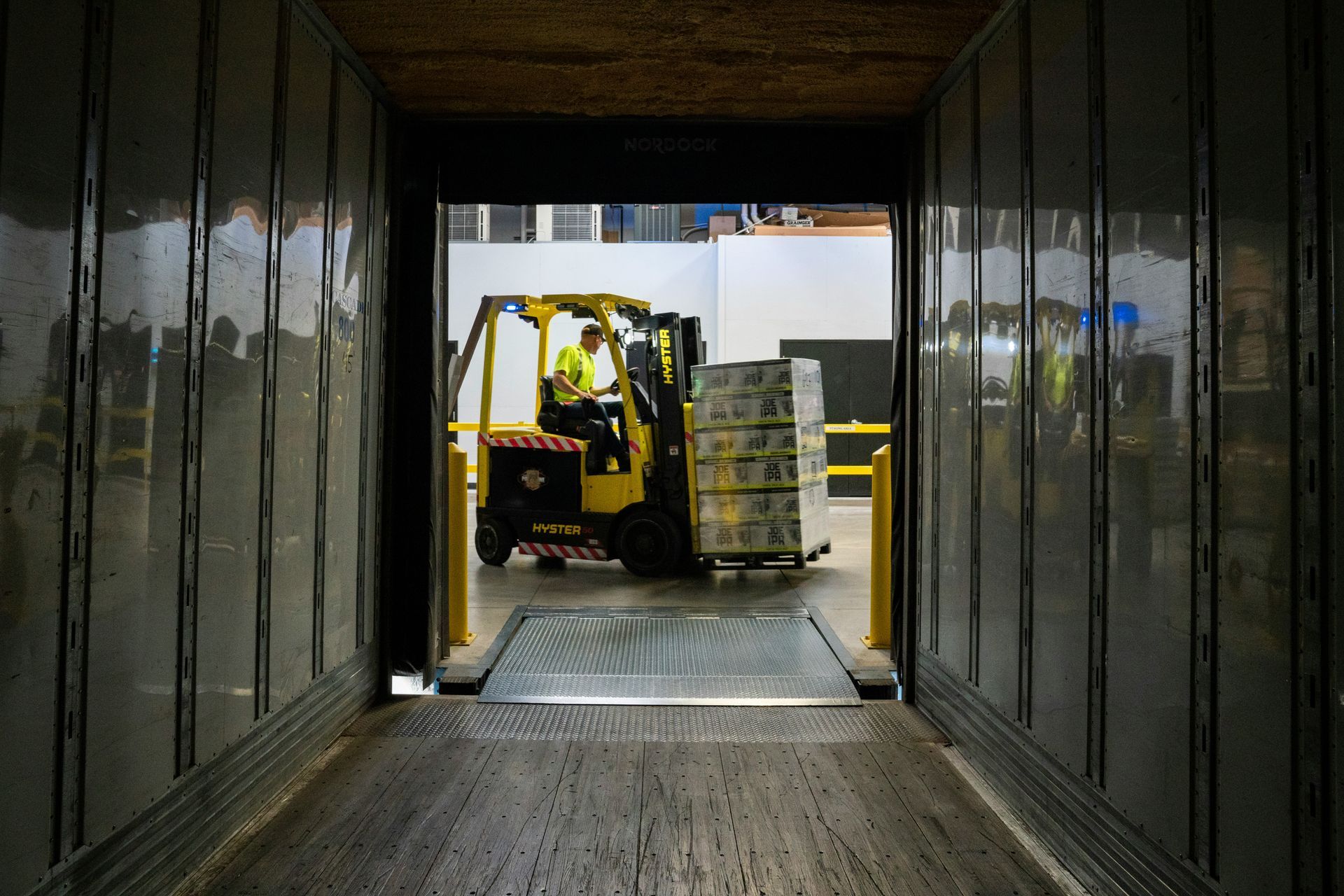 A forklift is loading boxes into a truck in a warehouse. 