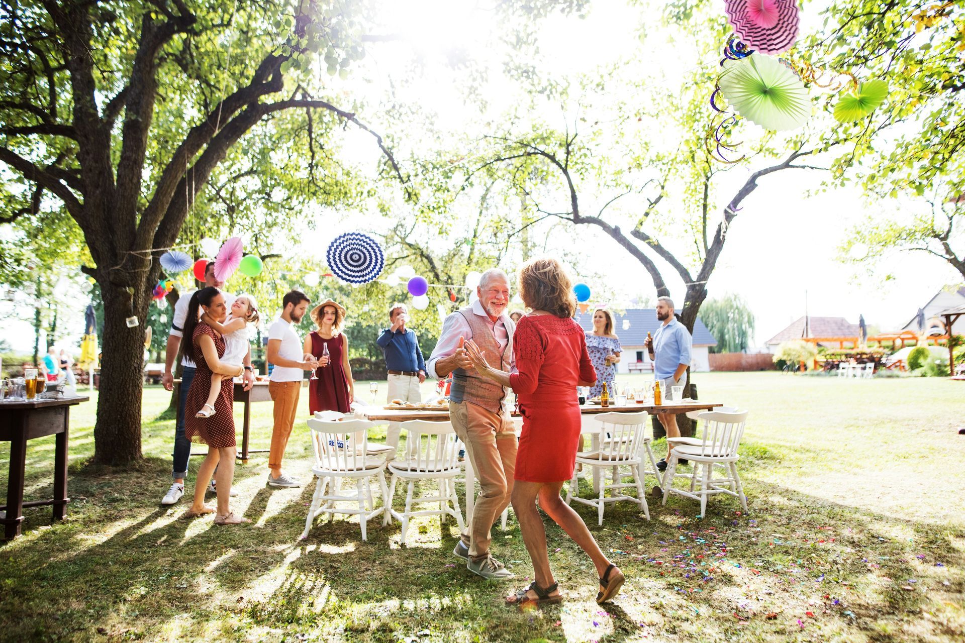 A group of people are dancing in a park at a party.