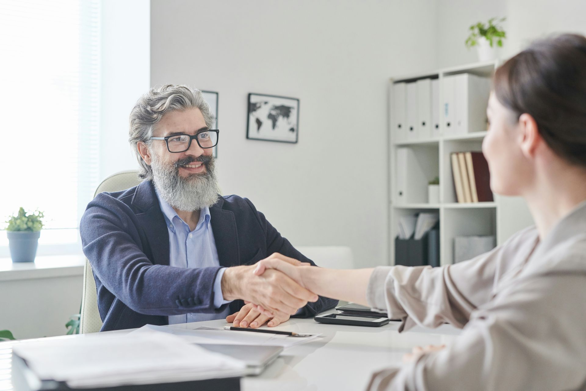 A man and a woman are shaking hands during a job interview. 