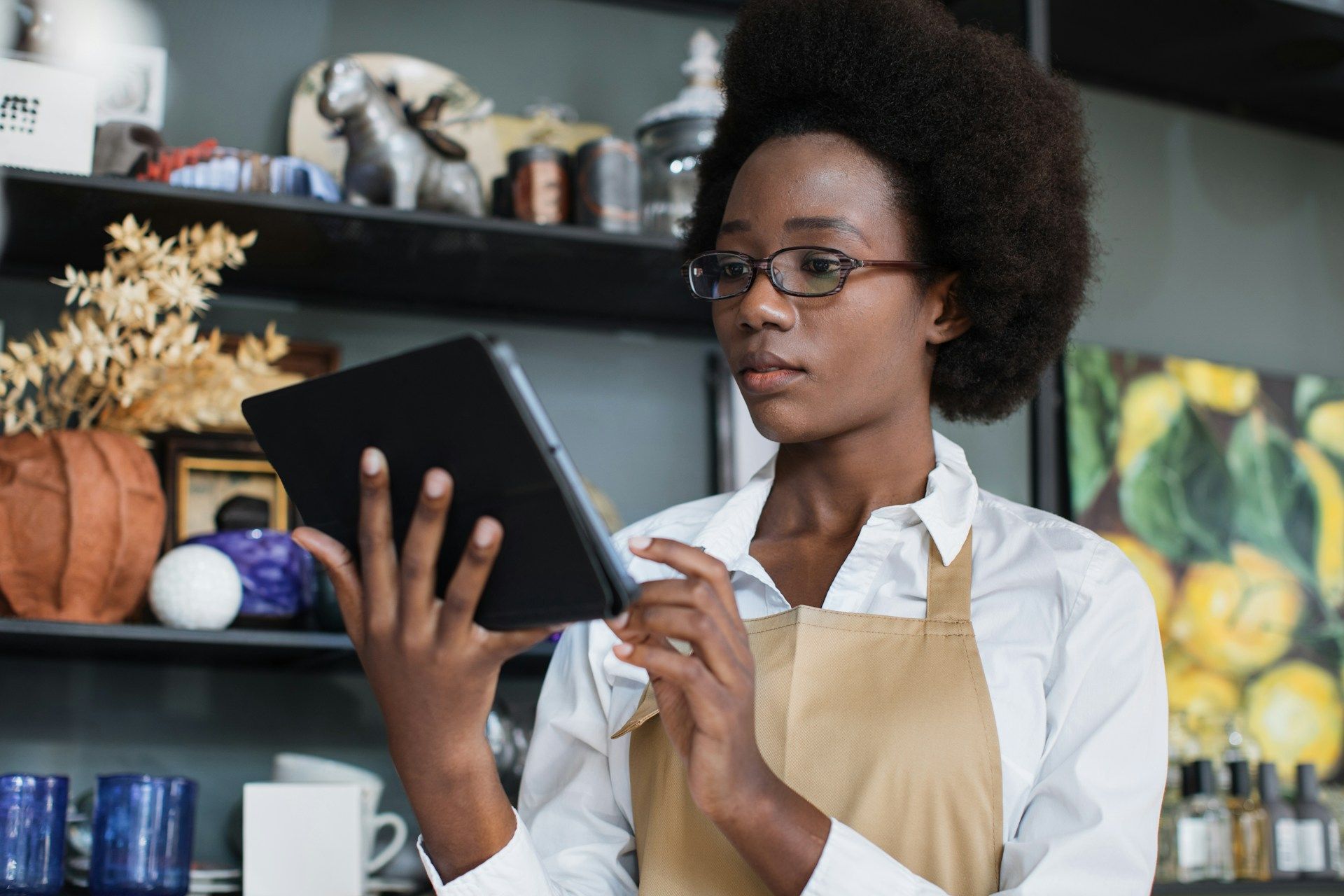 A woman in an apron is using a tablet computer in a kitchen.