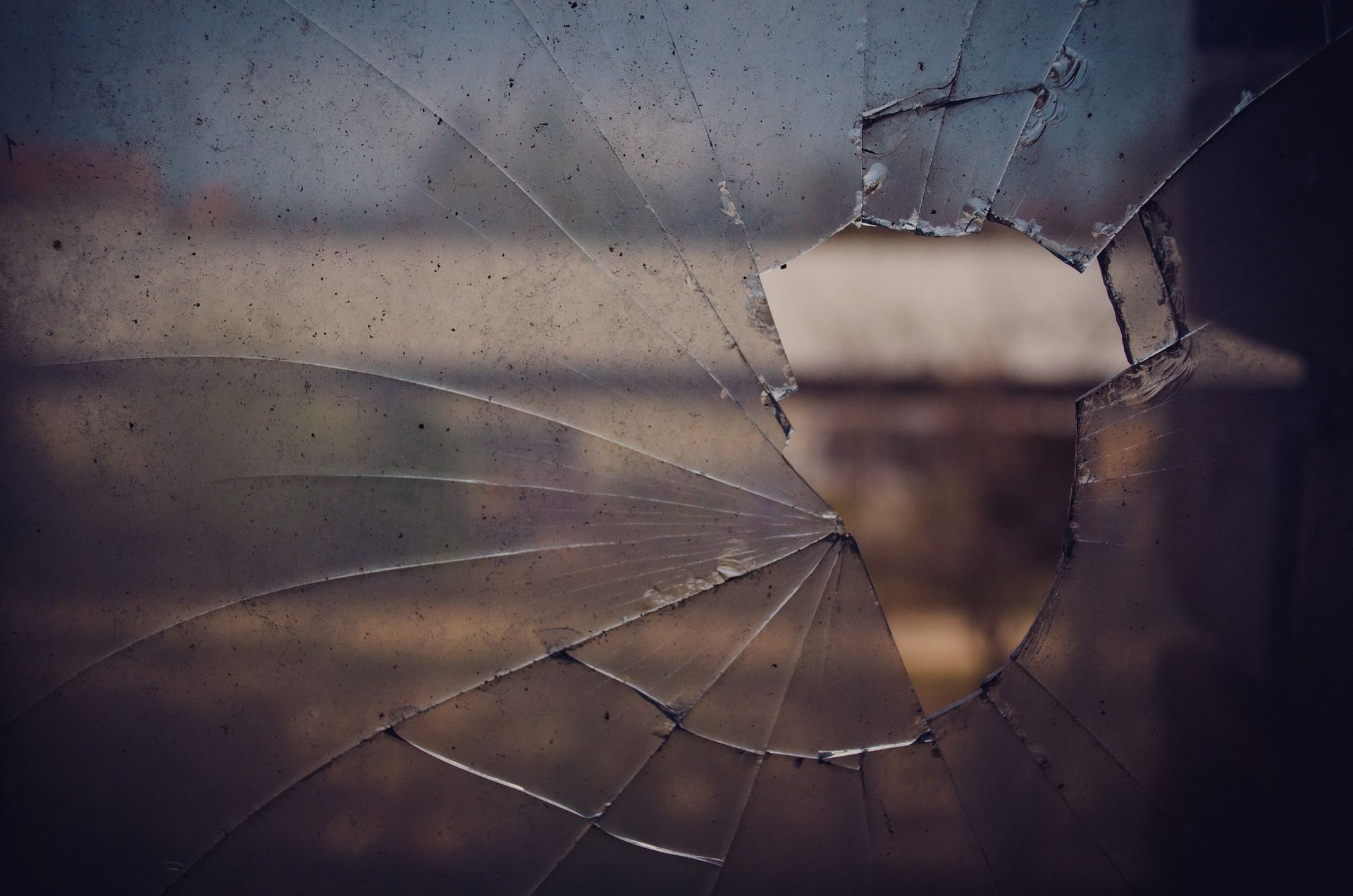 A close up of a broken glass window with a hole in it. 