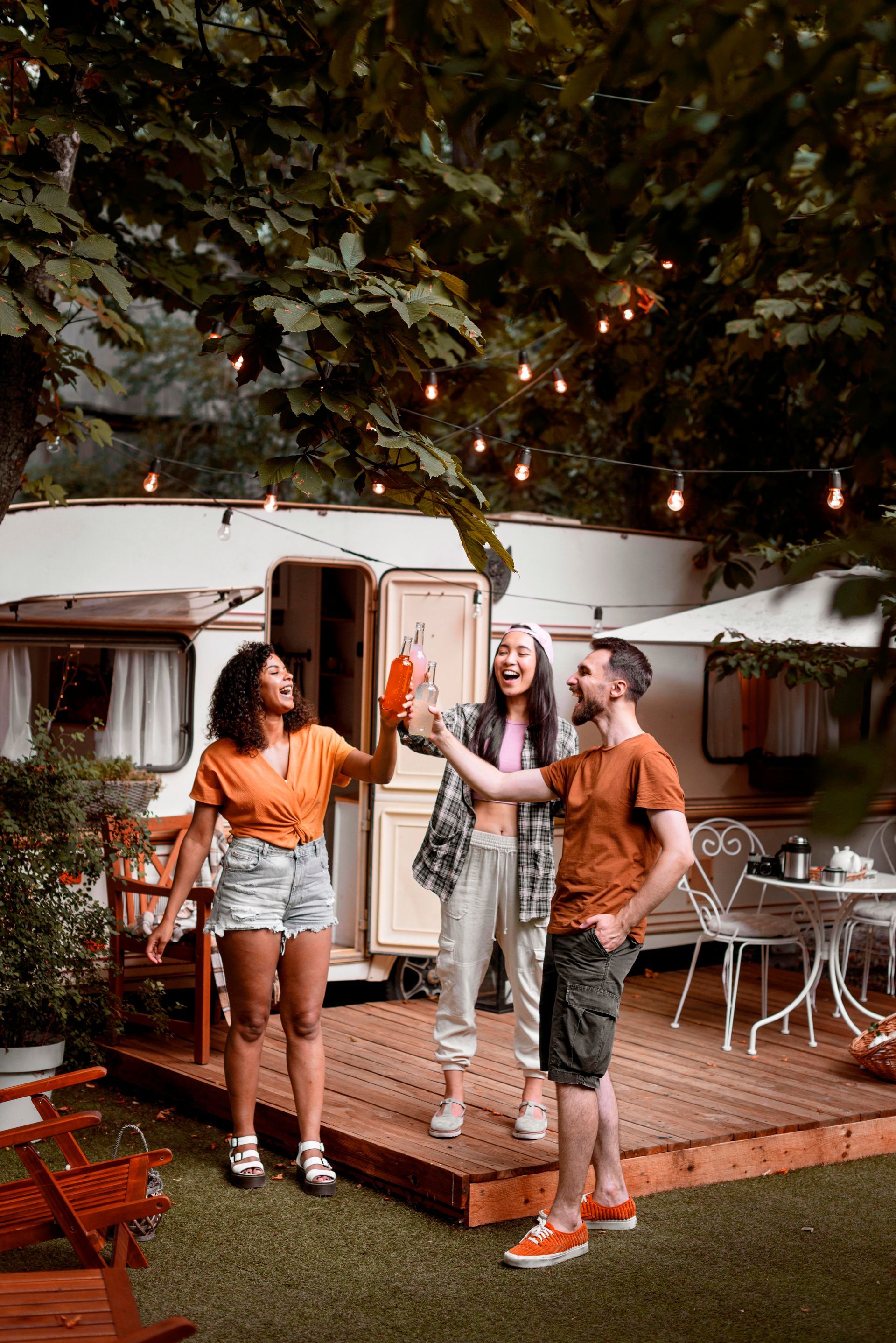 A group of people are standing on a deck in front of a trailer. 