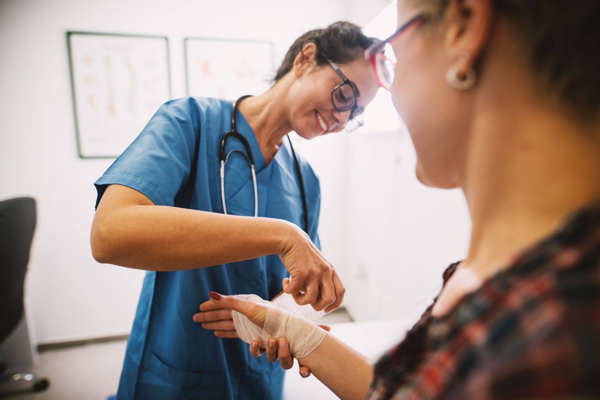 A nurse is bandaging a patient 's wrist in a hospital. 