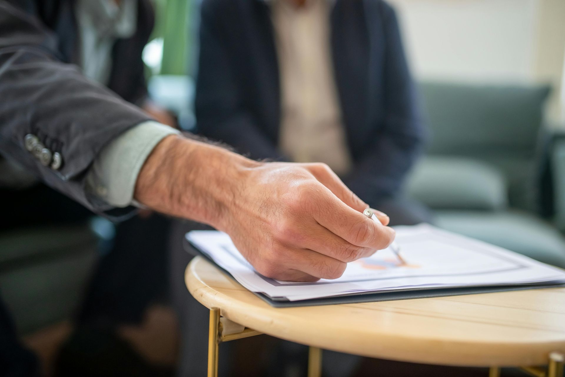 A man is signing a document on a table. 