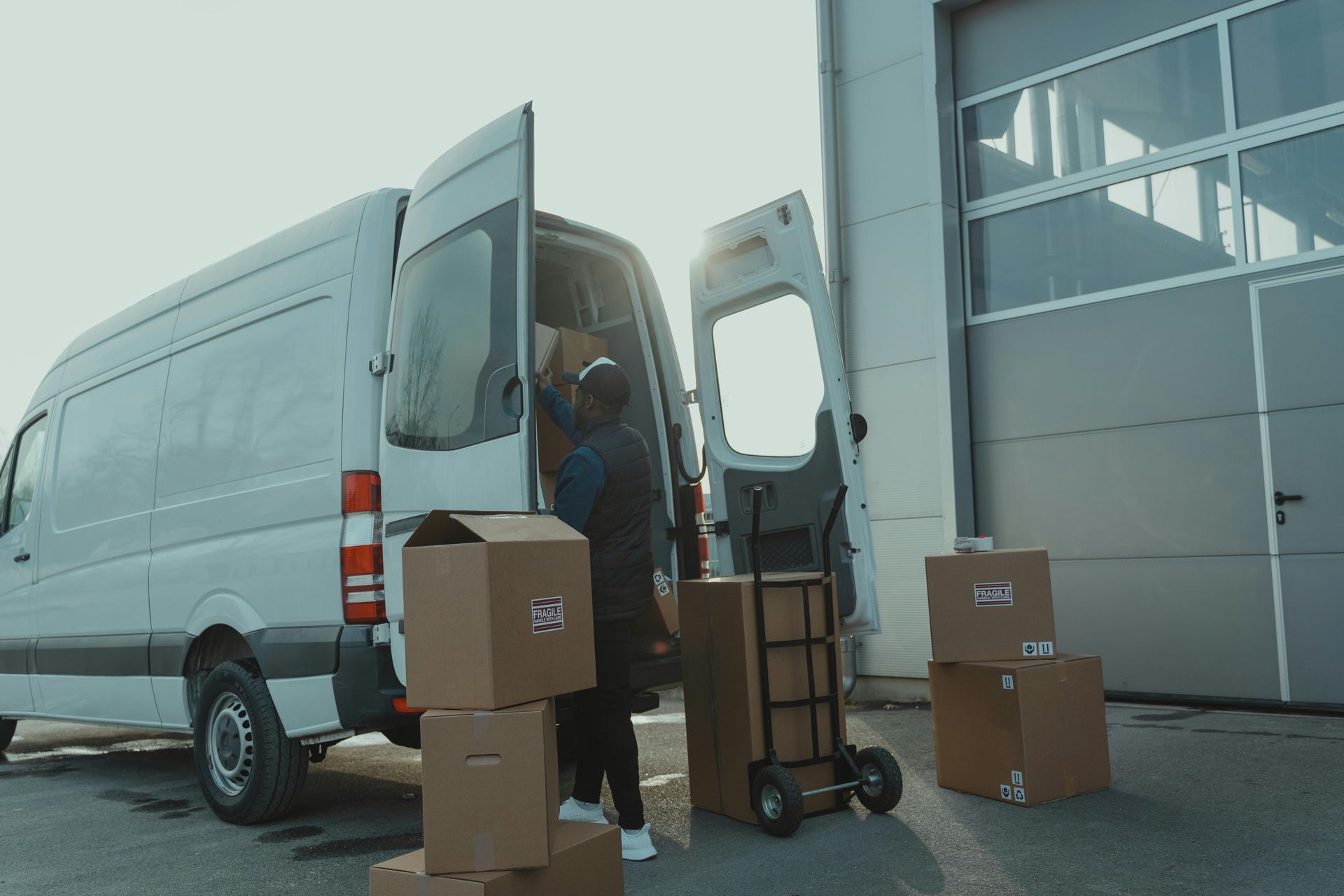 A man is loading boxes into a delivery van. 