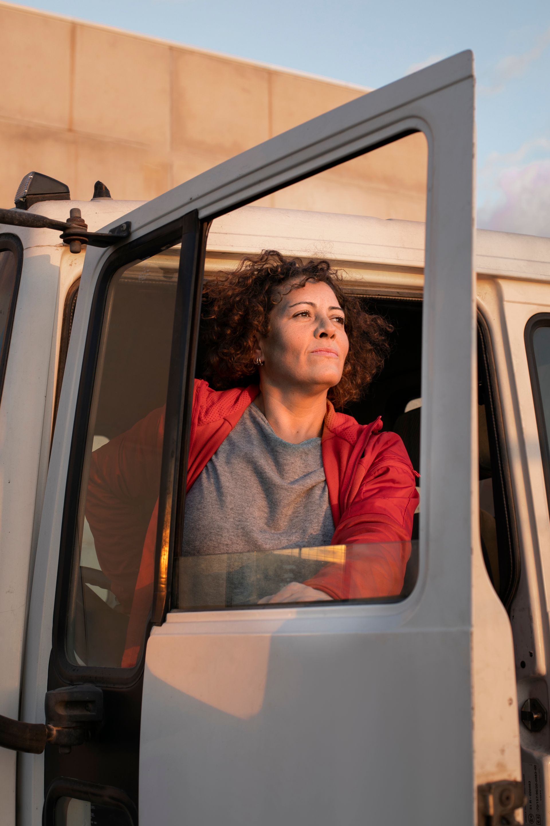 A woman is sitting in the driver 's seat of a truck. 