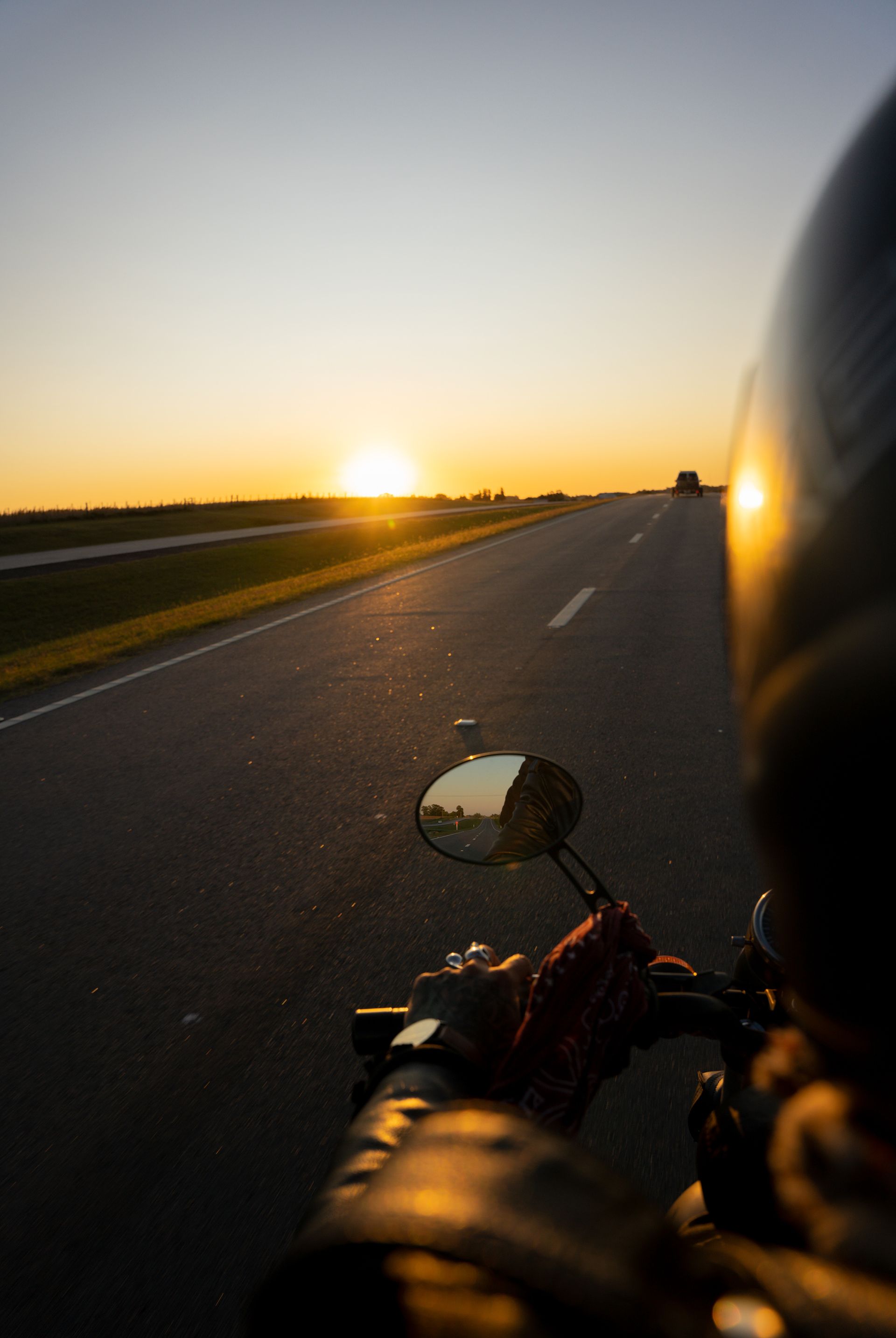 A person is riding a motorcycle down a highway at sunset. 