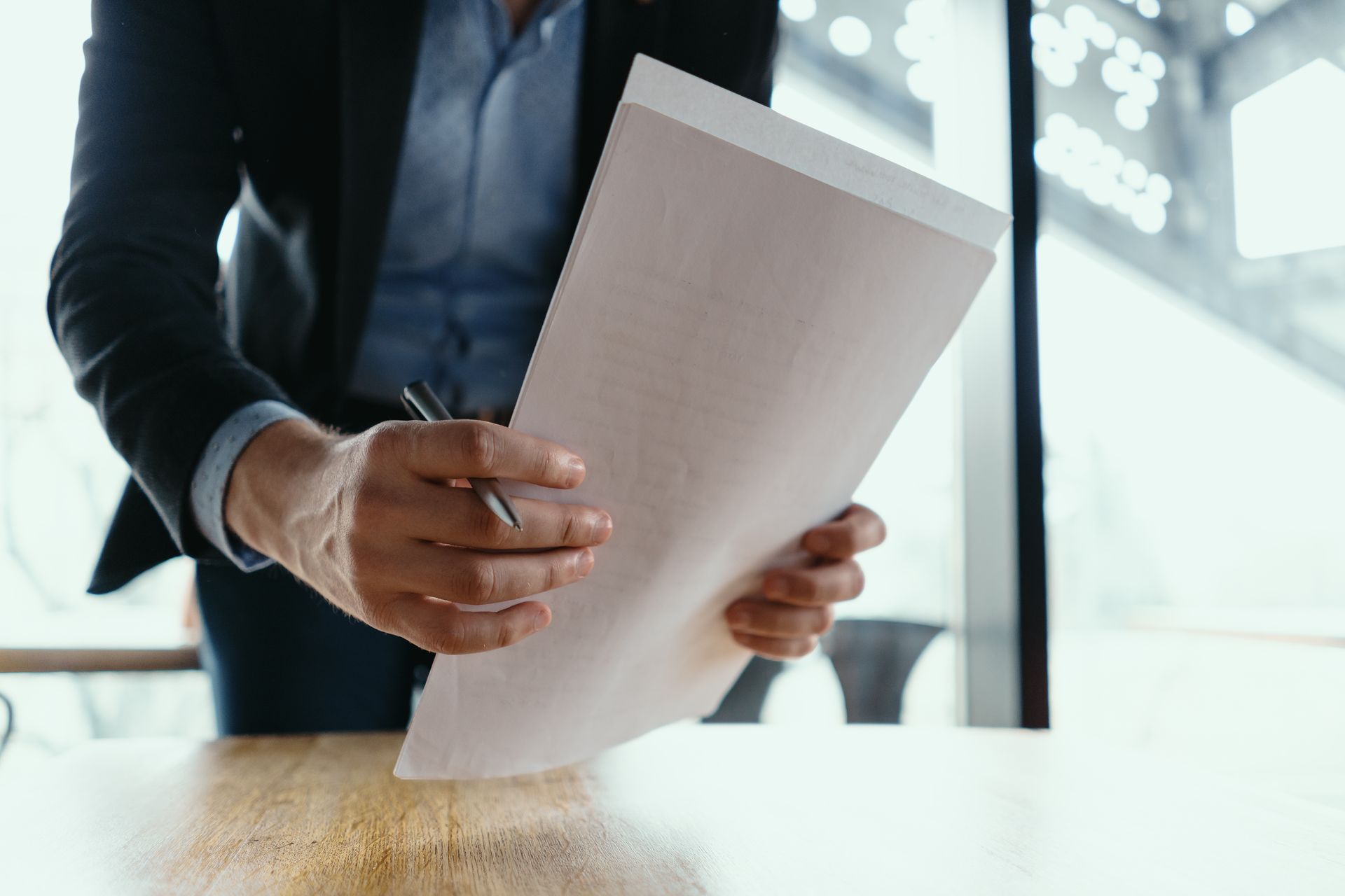A man is sitting at a table holding a piece of paper and a pen. 