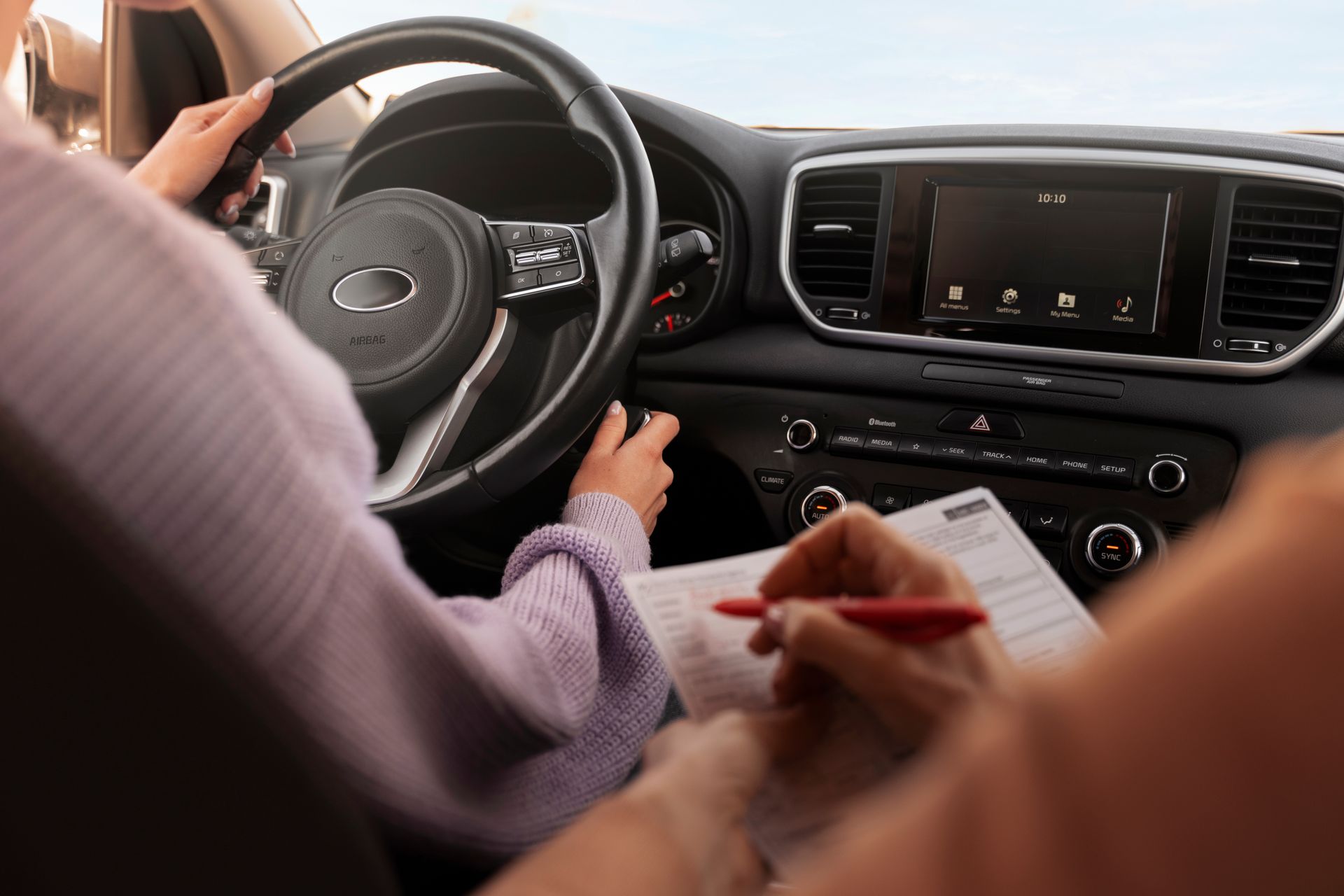 A person is sitting in a car writing on a piece of paper.  