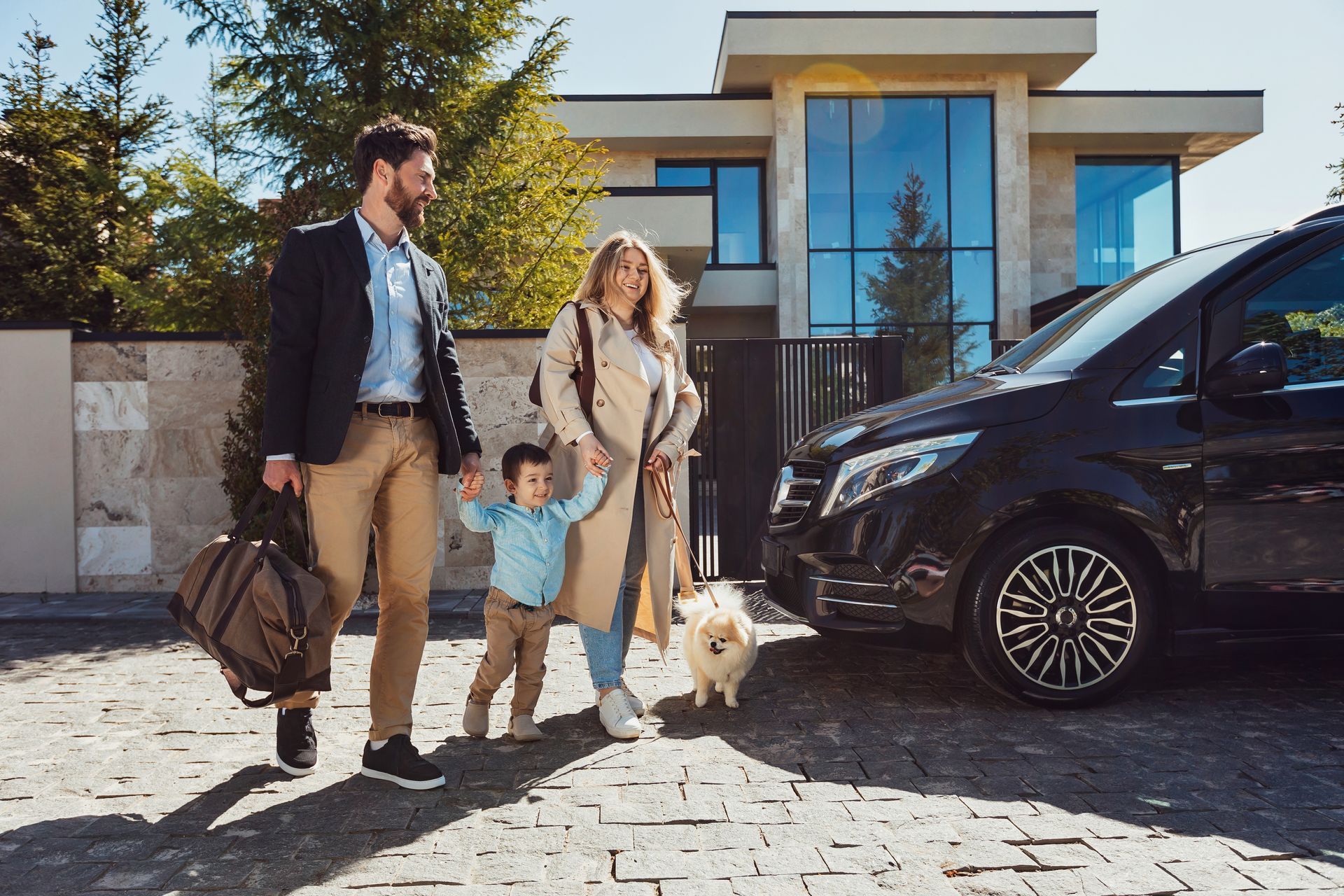 A family is walking towards a car in front of a house. 