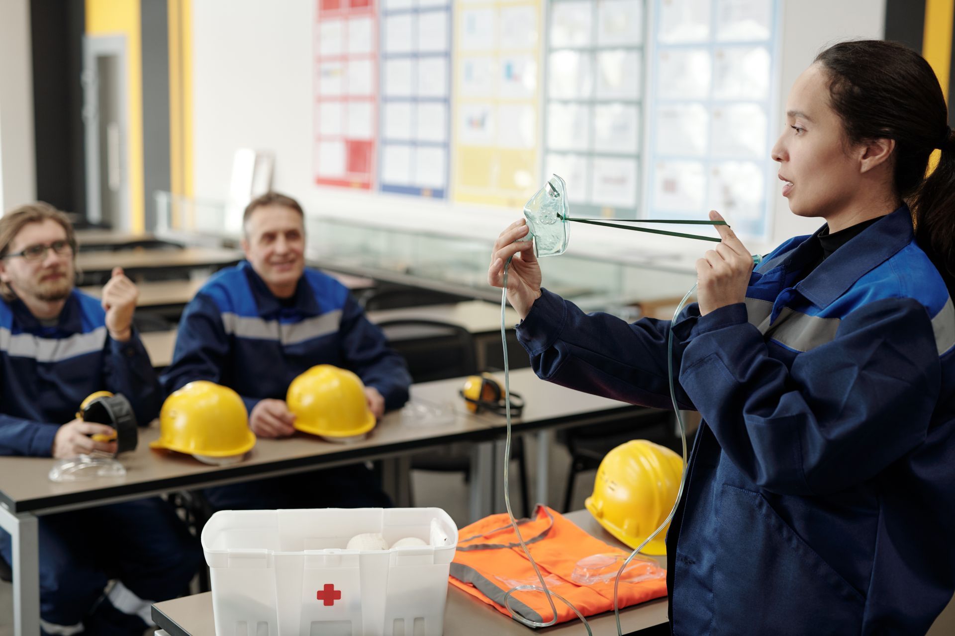 A woman is giving a presentation to a group of construction workers in a classroom. 