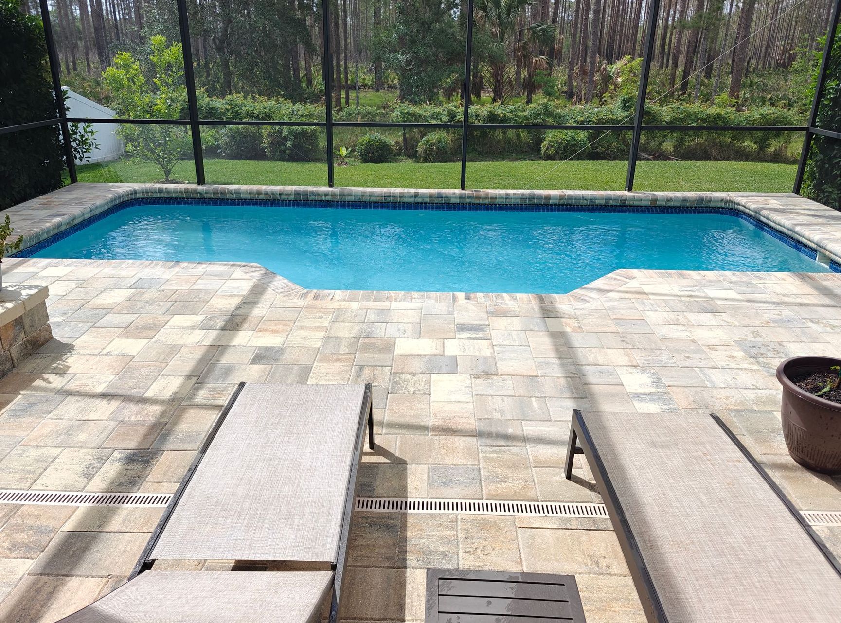 Paver pool deck with lounge chairs.