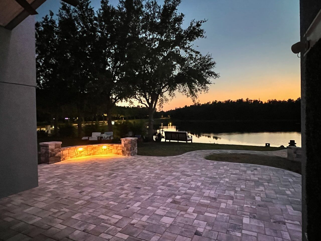 Paver patio with sitting wall lit up at dusk.