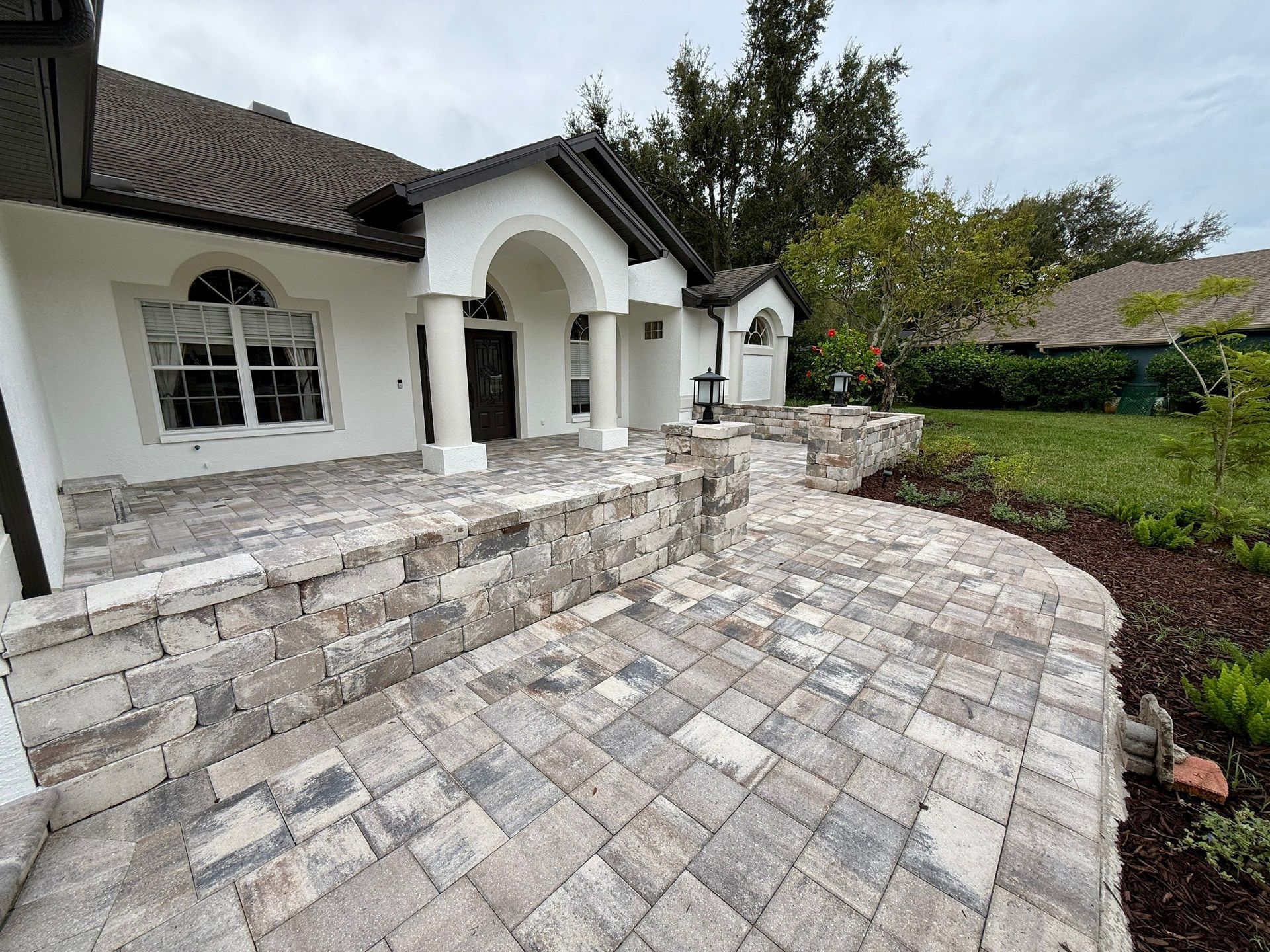 White Tan Charcoal Tumbled wall with matching pavers creating a front courtyard in Odessa, FL
