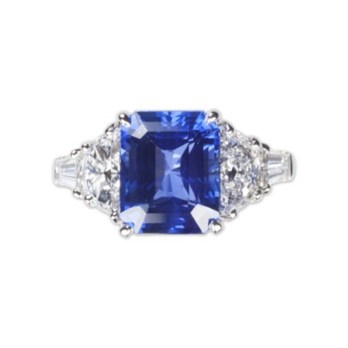 Blue square-cut gemstone ring with clear side stones on a silver band