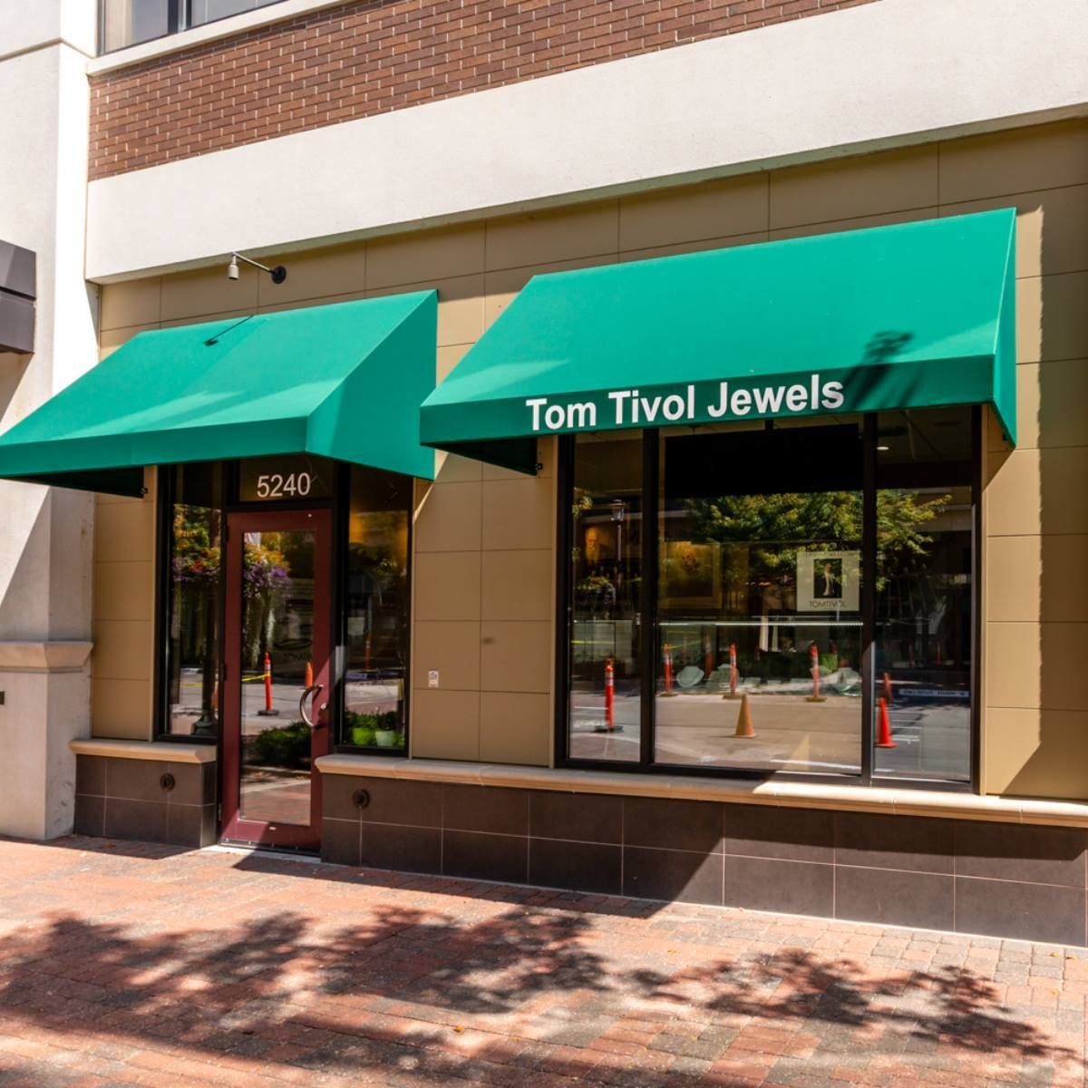 Tom Tivol Jewels storefront with green awnings on a sunny street corner