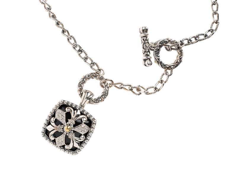 Silver necklace with a black floral pendant and central stone on a white background