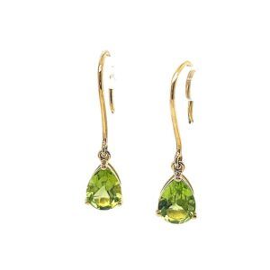 Pair of gold dangling earrings with green teardrop gemstones on a white background