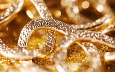Close-up of intertwined gold rings with textured surfaces on a sparkling golden background