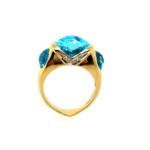 Gold ring with a large blue gemstone and side stones on a white background