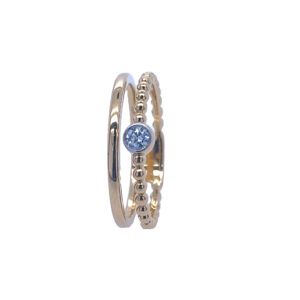 Gold and silver stacked rings with a small blue gemstone center