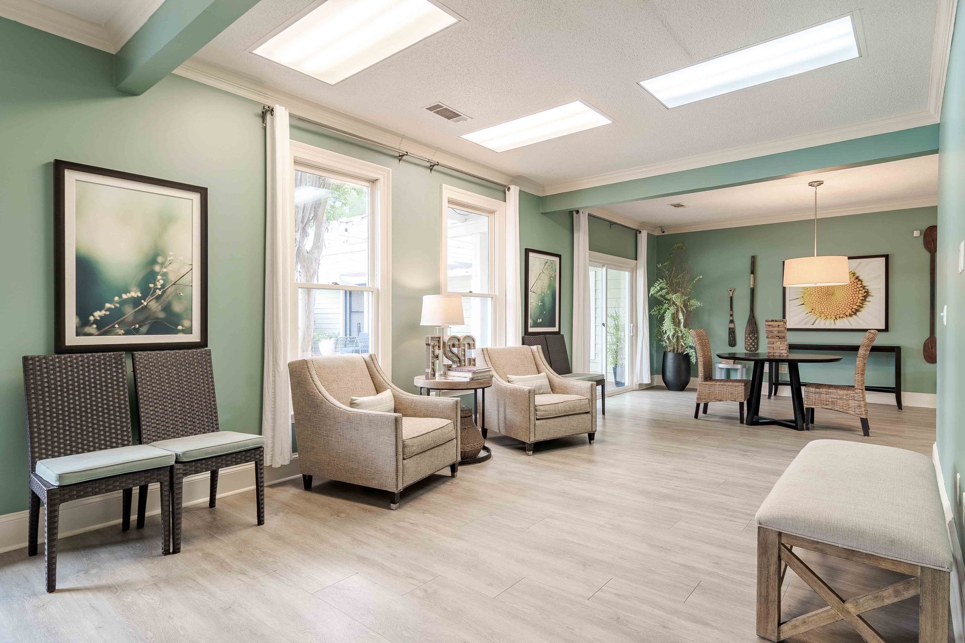 Waiting room with chairs, art, and windows, painted light green, and wooden floor.