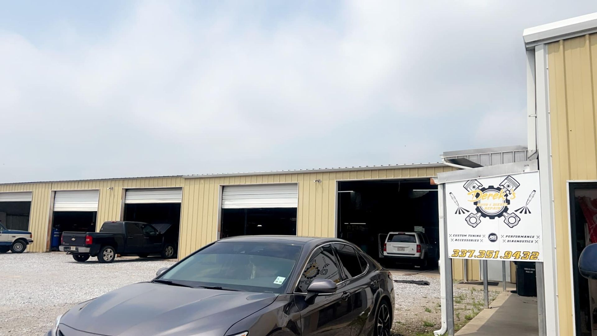 A gray car is parked in front of a garage.