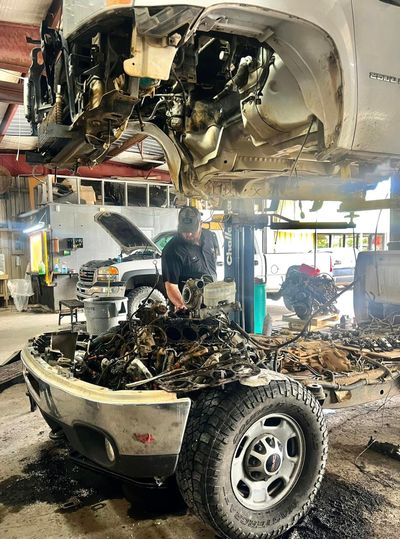 A man is working on the engine of a car in a garage.