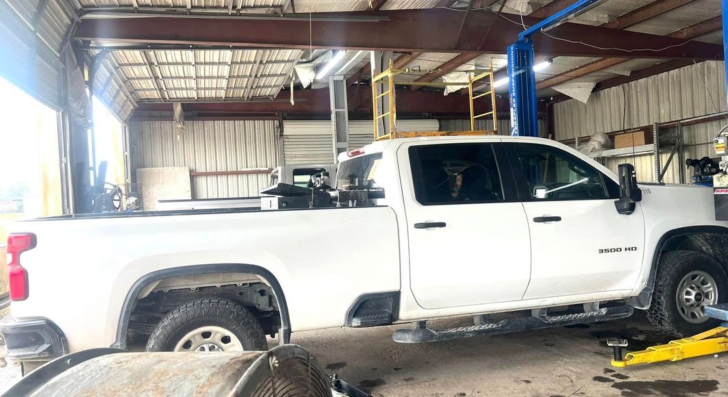 A white truck is sitting on a lift in a garage.