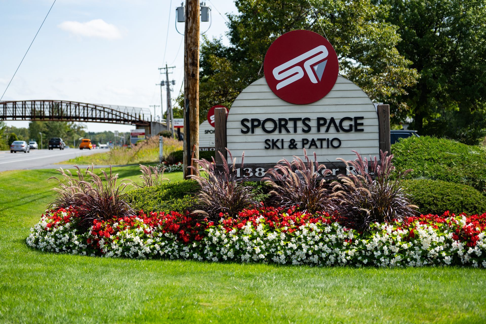 A sign for sports page ski and patio is surrounded by flowers