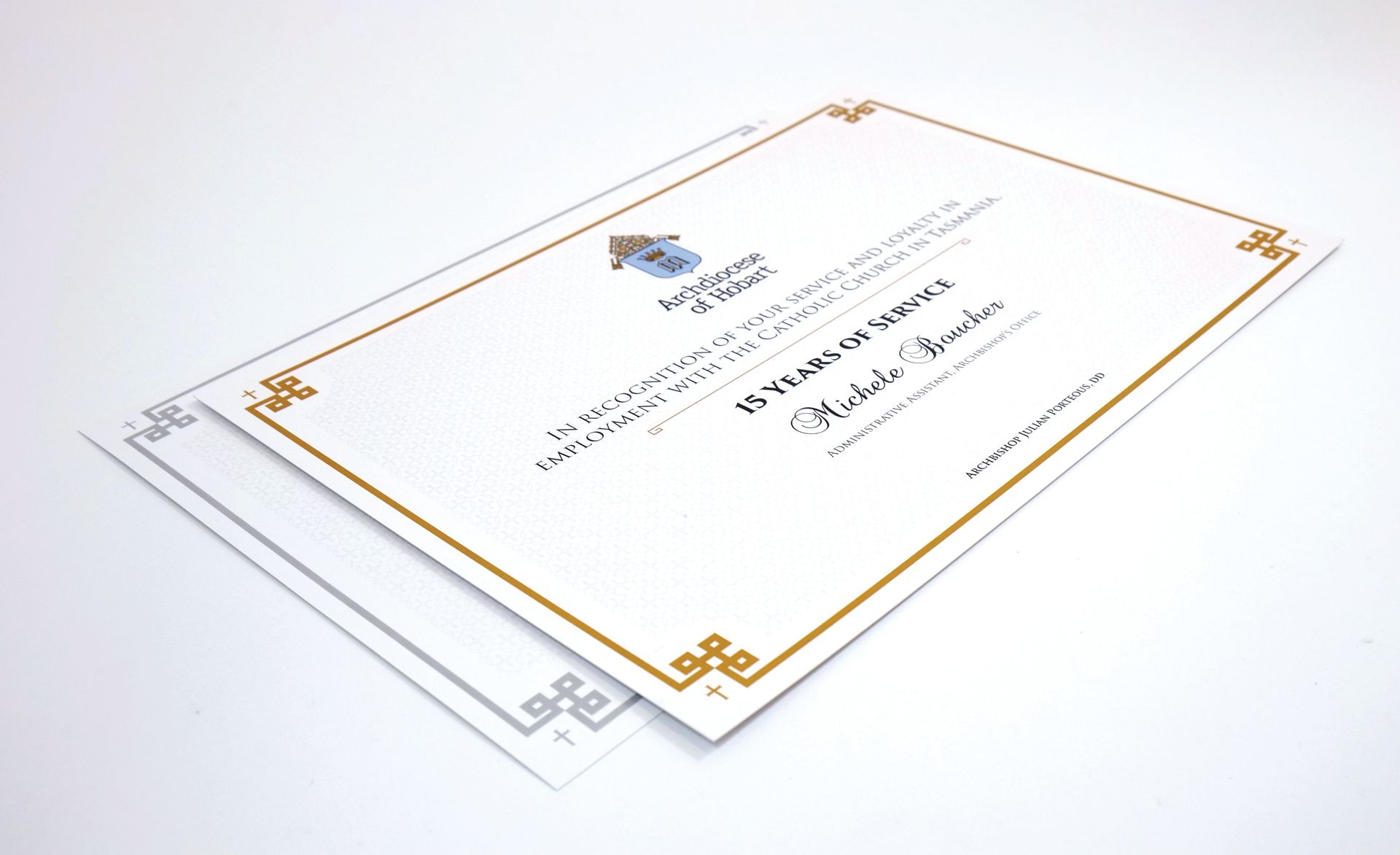 Two certificates, one with a gold border, and the other with a silver border, on a white surface.