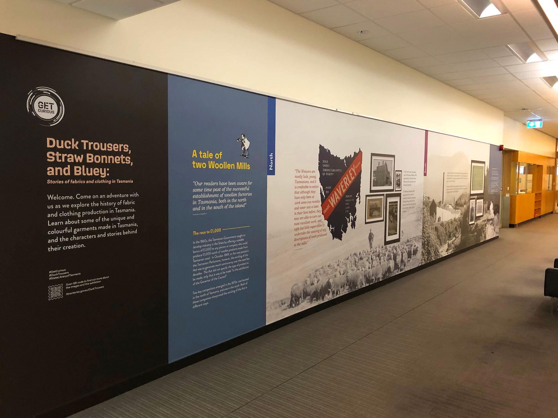 Long hallway with a timeline display on the wall, showing text, maps, and photographs.