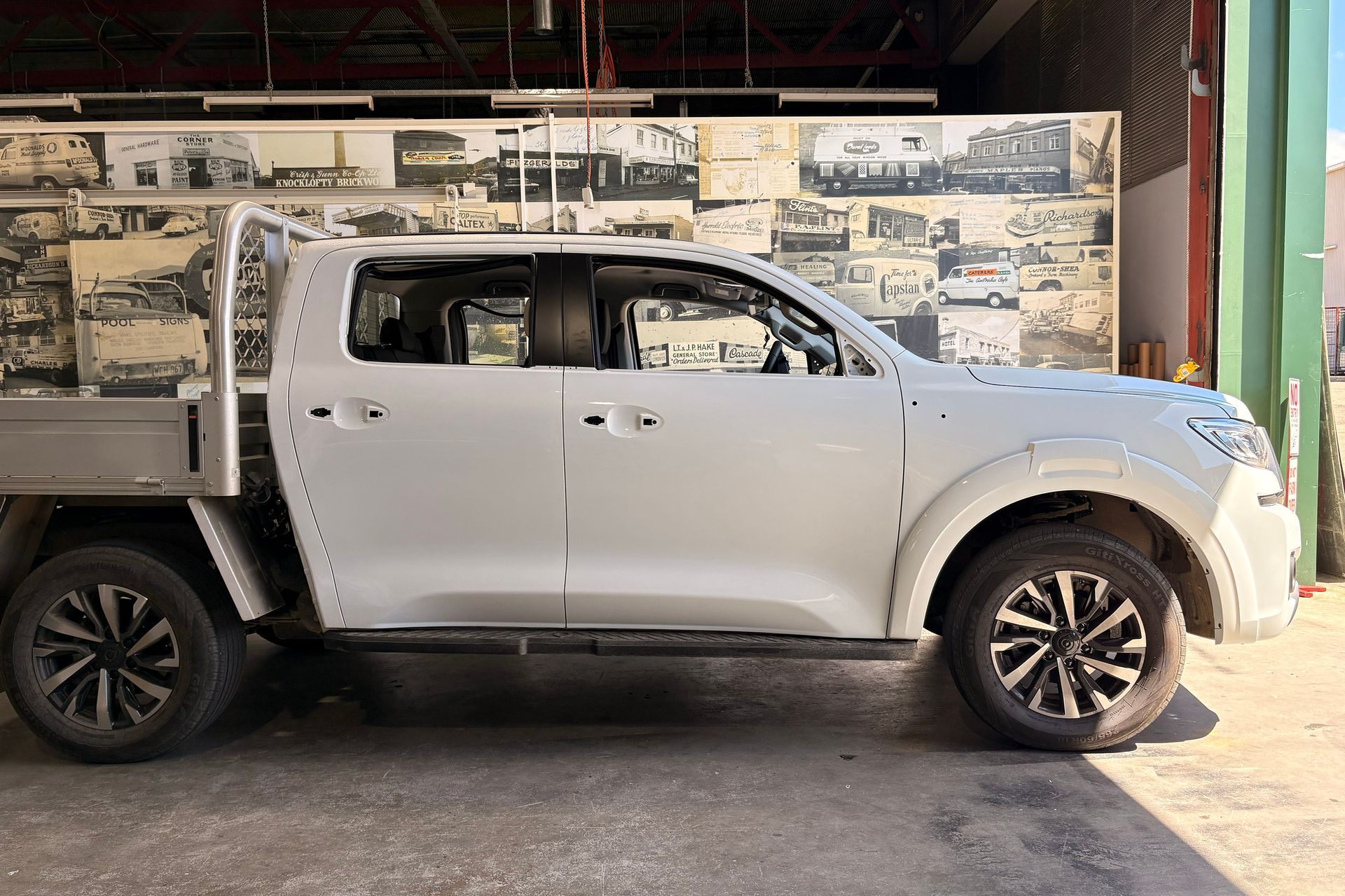White pickup truck parked inside a building with a metal wall before carwrap