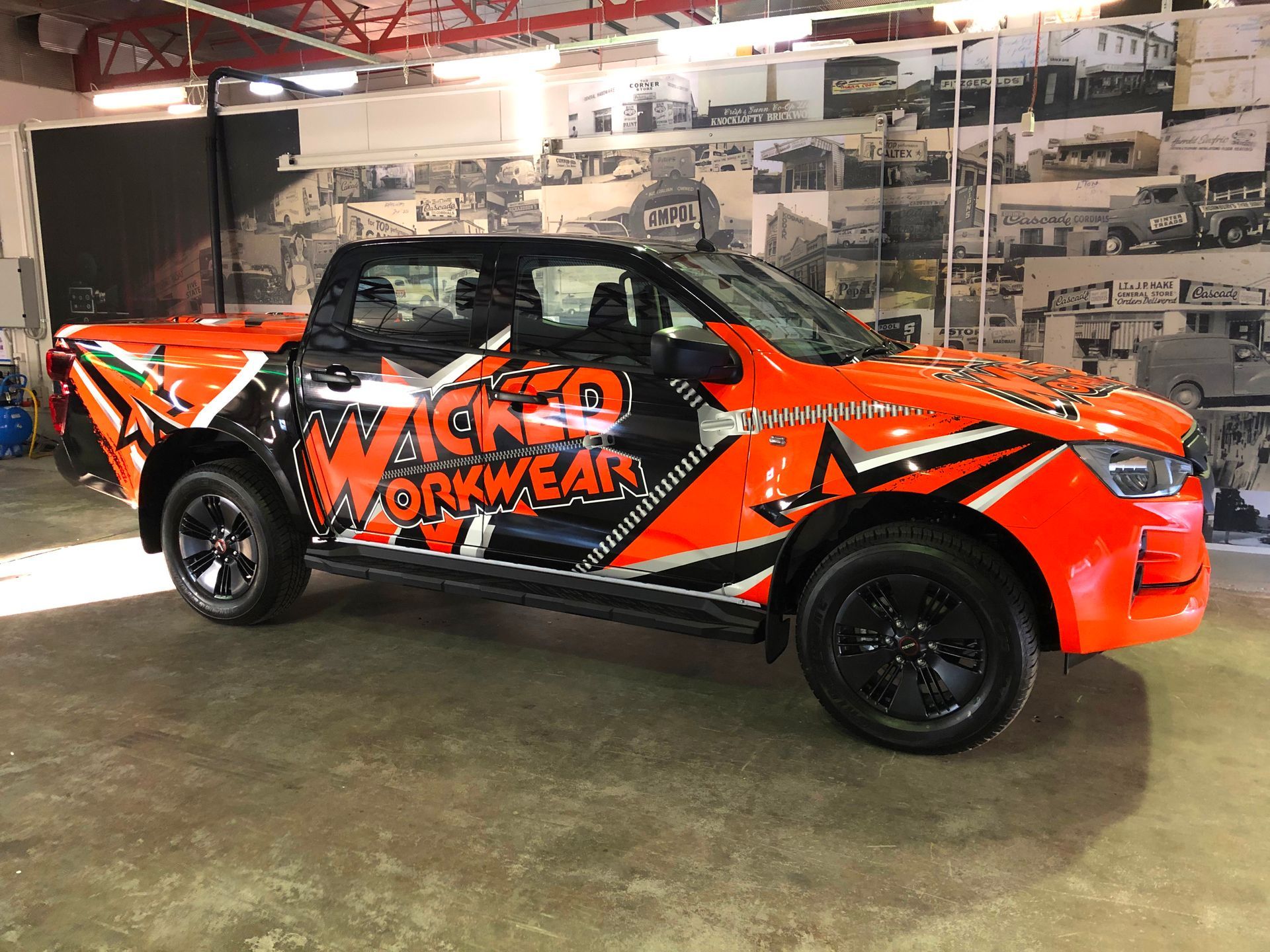Orange and black Wicked Workwear pickup truck parked in a shop.