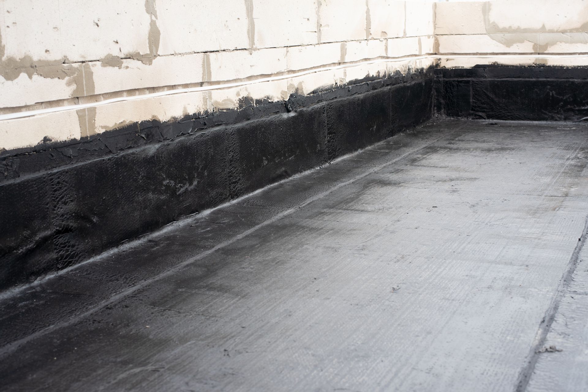 A black concrete floor with a brick wall in the background.