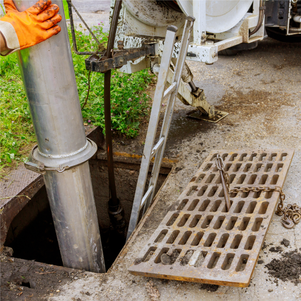 A man is cleaning a drain with a vacuum truck.