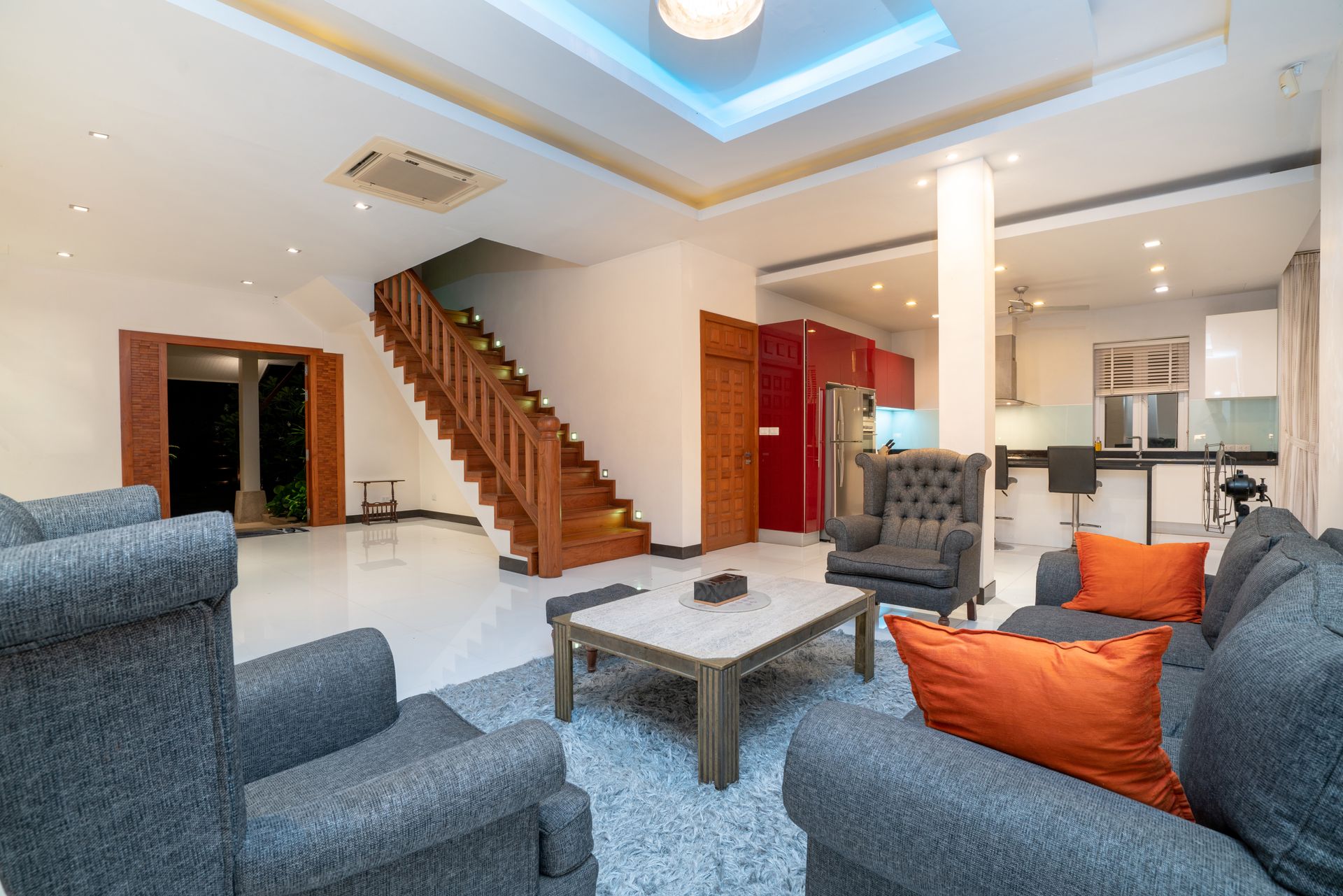 A living room with a couch , chairs , coffee table and stairs.