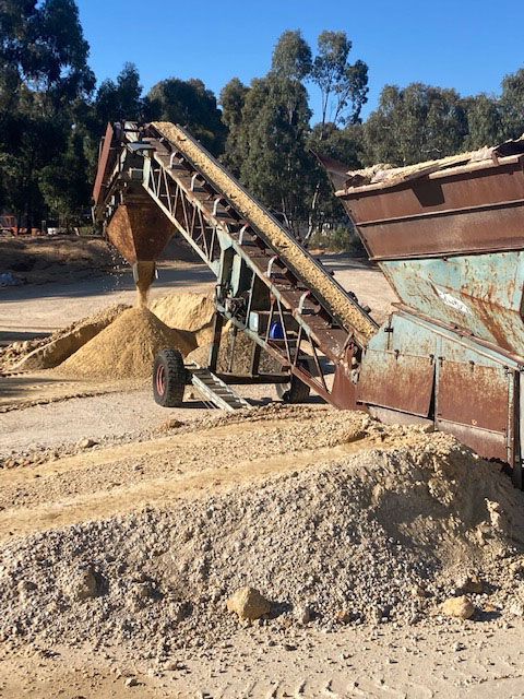 A conveyor belt is moving dirt in a dirt field.