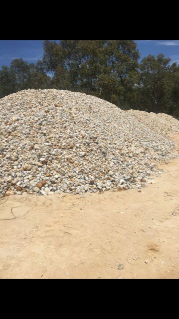 A large pile of rocks is sitting on top of a dirt field.