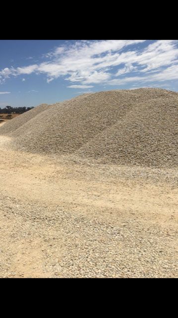 A large pile of gravel is sitting on top of a dirt field.
