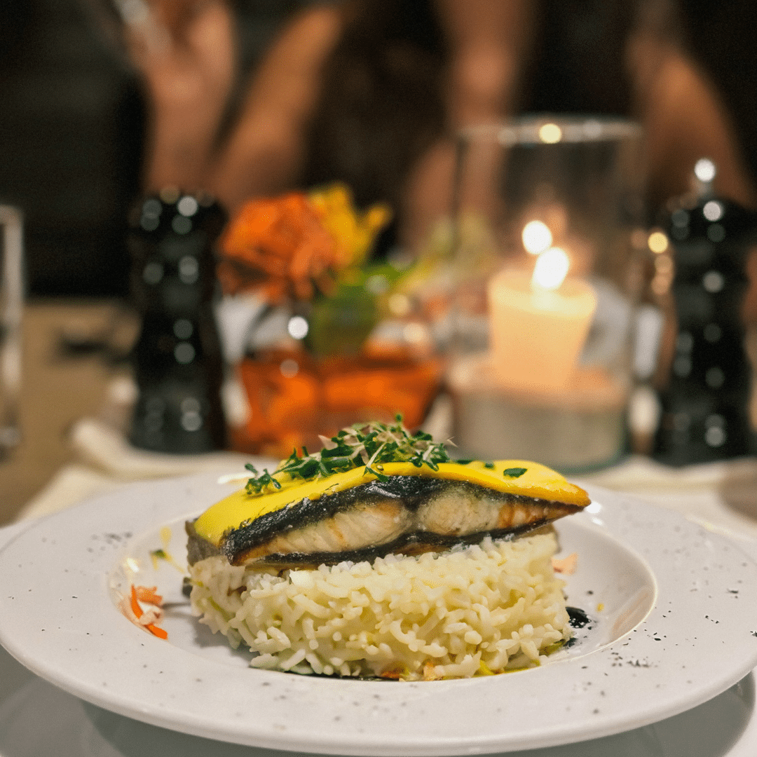 Un plato de comida en una mesa con una vela al fondo.