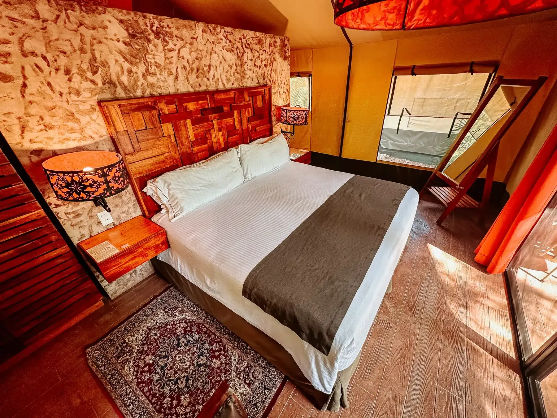 Un dormitorio con una cama, lámparas y una gran ventana.